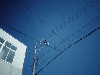Low angle view of electricity pylon against blue sky