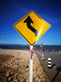 Yellow road sign on beach against clear blue sky