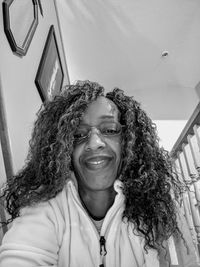 Low angle portrait of woman with curly hair at home