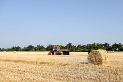 Hay bales on field against clear sky