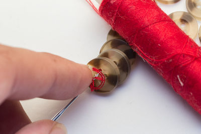 High angle view of person hand holding buttons in needle on table