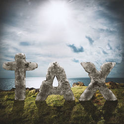 Panoramic view of cross on shore against sky