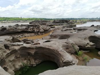 Scenic view of rocks on shore against sky