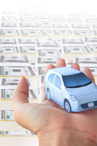 Close-up of person holding toy car against currency