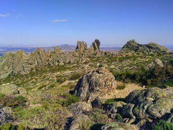 Rock formations on landscape against clear blue sky