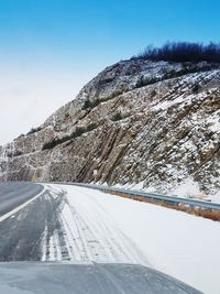 Road by snow covered mountain against sky