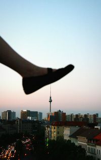 Optical illusion of cropped leg touching fernsehturm at sunset