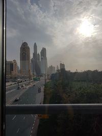 Road by buildings in city against sky