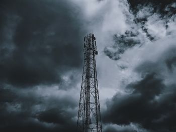 Low angle view of communications tower against cloudy sky