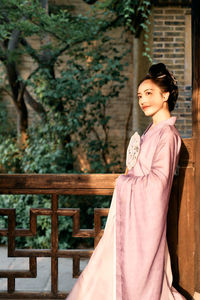 Portrait of young woman standing against trees