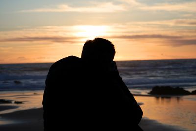 Silhouette man on beach against sky during sunset
