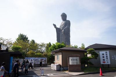 Statue by building against sky