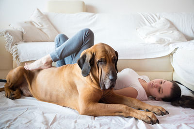 Young woman by dog relaxing on bed at home