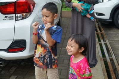 Siblings standing by car at parking lot