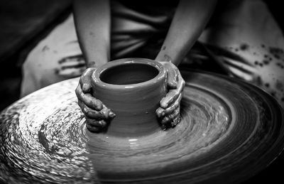 Midsection of potter making pot on pottery wheel at workshop