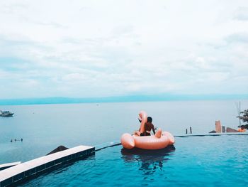 Young woman in swimming pool against sky