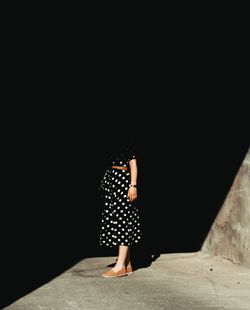 Full length of woman standing against black wall