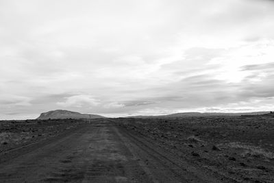 Dirt road along landscape against sky