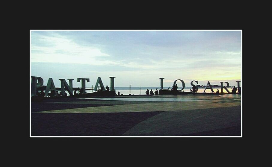 text, sky, western script, cloud - sky, communication, cloud, built structure, no people, cloudy, sign, architecture, art, railing, day, bicycle, outdoors, capital letter, silhouette, sunlight, transportation