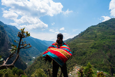 Rear view of woman looking at mountains against sky