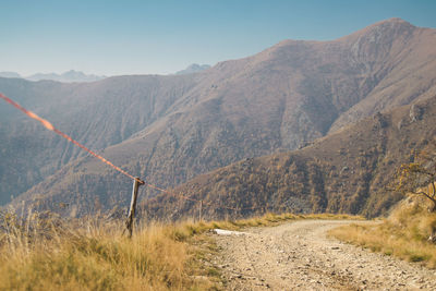 Empty dirt road against mountains