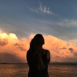 Rear view of woman looking at sea during sunset