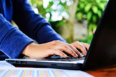 Midsection of businesswoman using laptop on table