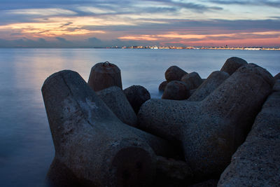 Rocks on beach against sky during sunset