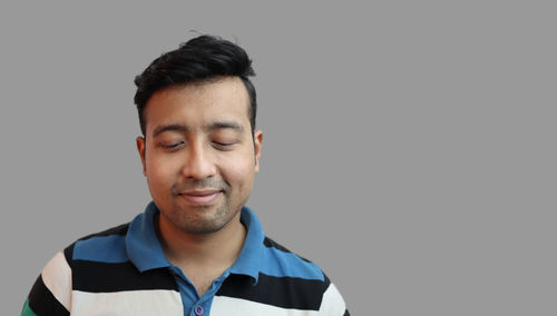 Portrait of young man standing against black background