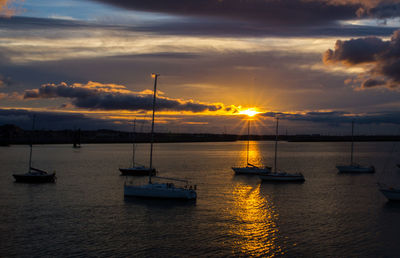 Sailboats in sea against sky during sunset