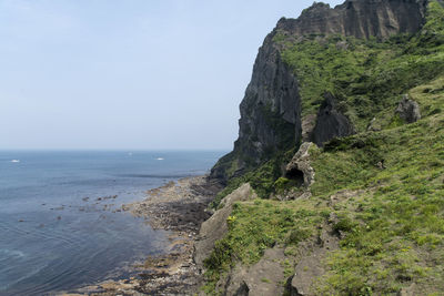 Rock formation by sea against sky