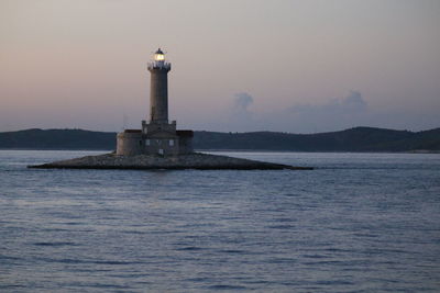 Lighthouse by sea against sky