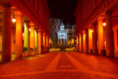 Illuminated street amidst buildings at night