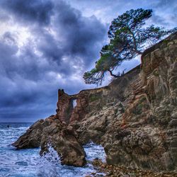 Low angle view of cliff by sea against sky