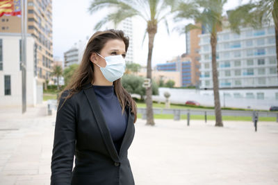 Attractive woman with executive look, walking out of work with protective surgical mask
