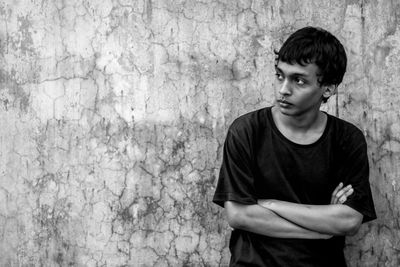 Man looking away while standing against wall