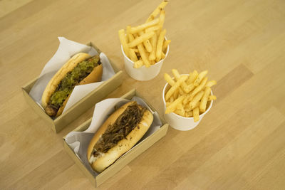 High angle view of french fries and hot dog on wooden table