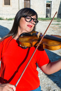 Close-up of young woman playing violin while standing outdoors