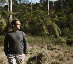 Man looking away while standing in forest