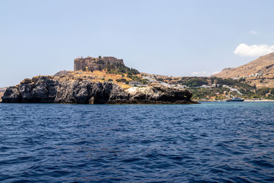 Sea by buildings against clear sky