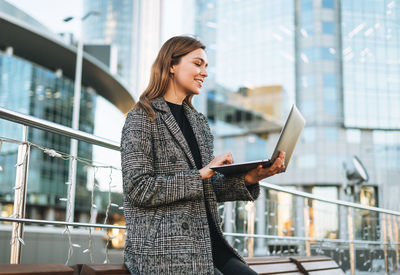 Portrait of young woman standing in city