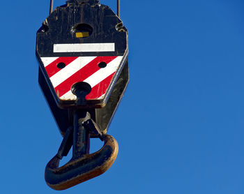 Low angle view of crane against clear blue sky