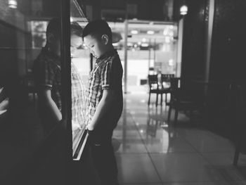 Side view of boy looking at display cabinet in restaurant