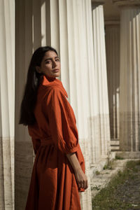 Side view portrait of fashionable young woman standing by columns