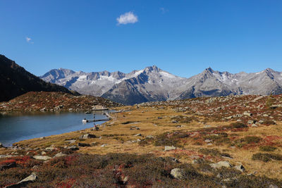 Scenic view of lake and mountains against blue sky