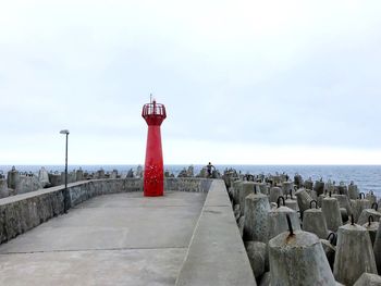 Lighthouse by sea against sky