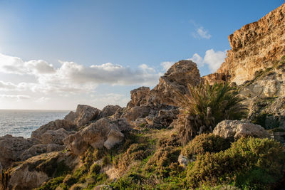 Rock formations by sea against sky