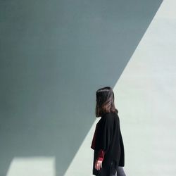 Side view of woman standing against wall