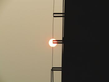 Low angle view of illuminated lamp against wall at night