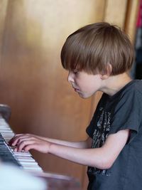 Side view of teenage girl playing piano